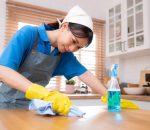 Young woman cleaning the table in the kitchen. Housekeeping and housekeeping concept.